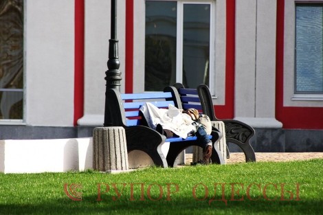 Бомж, уснувший на одной из скамеек возле стадиона, выглядит как-то по европейски